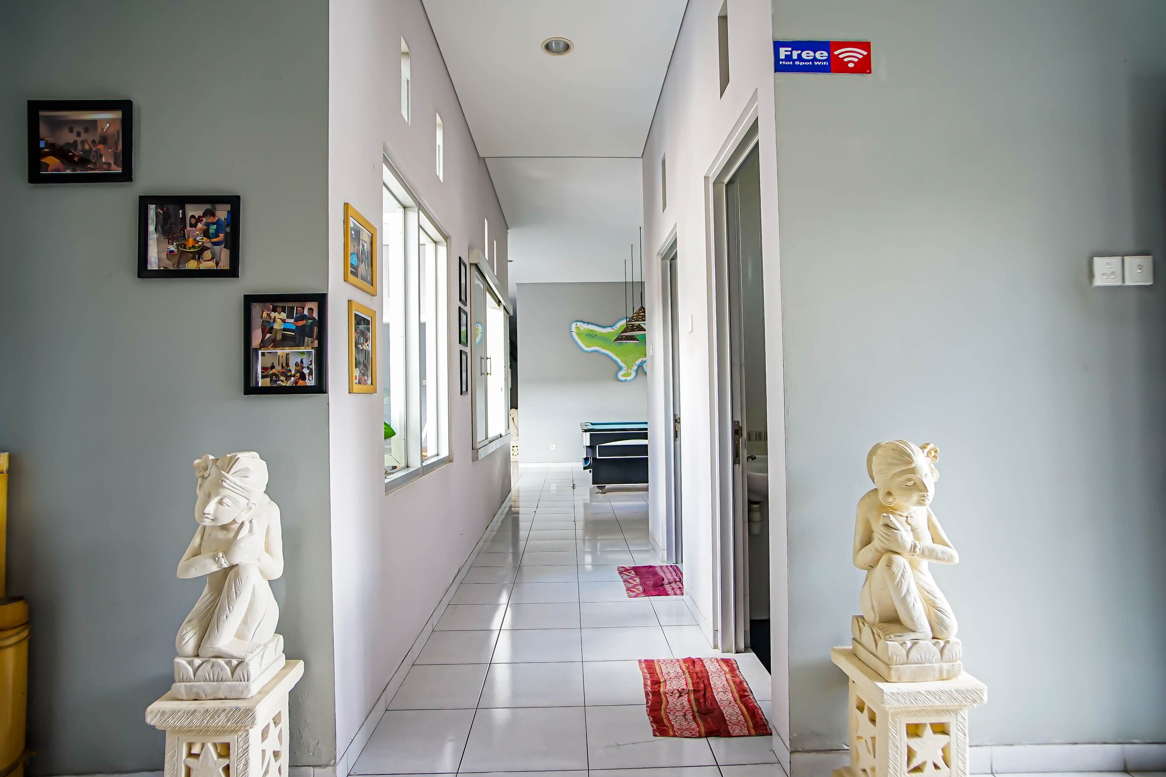 A hallway with two statues, a flat-screen TV, and a bed in the distance.