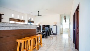 A modern kitchen with granite countertops, wooden stools, and a dining area with a table and chairs. - DD Living - Hostel (Tibubeneng)