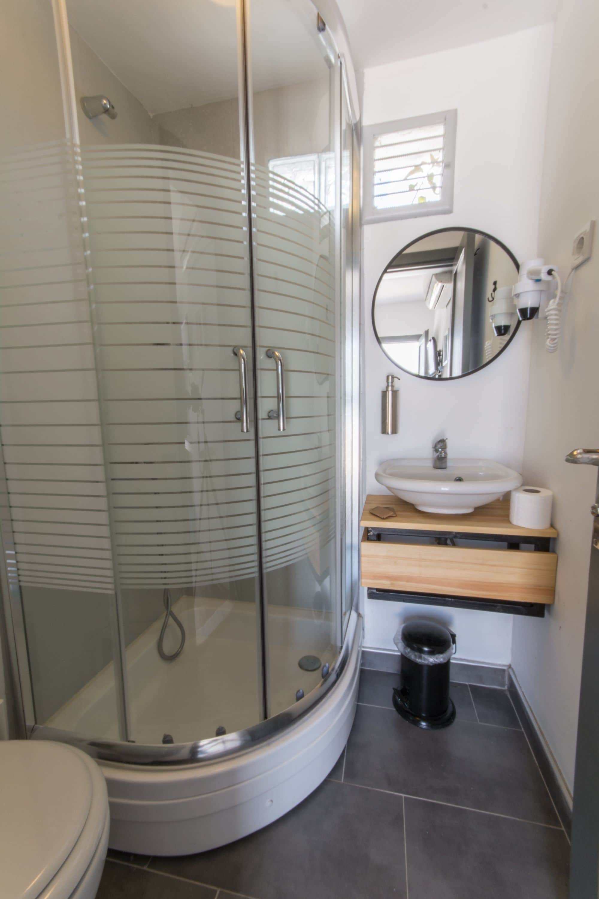 A modern bathroom with a glass-enclosed shower, a white sink, and a mirror above it.