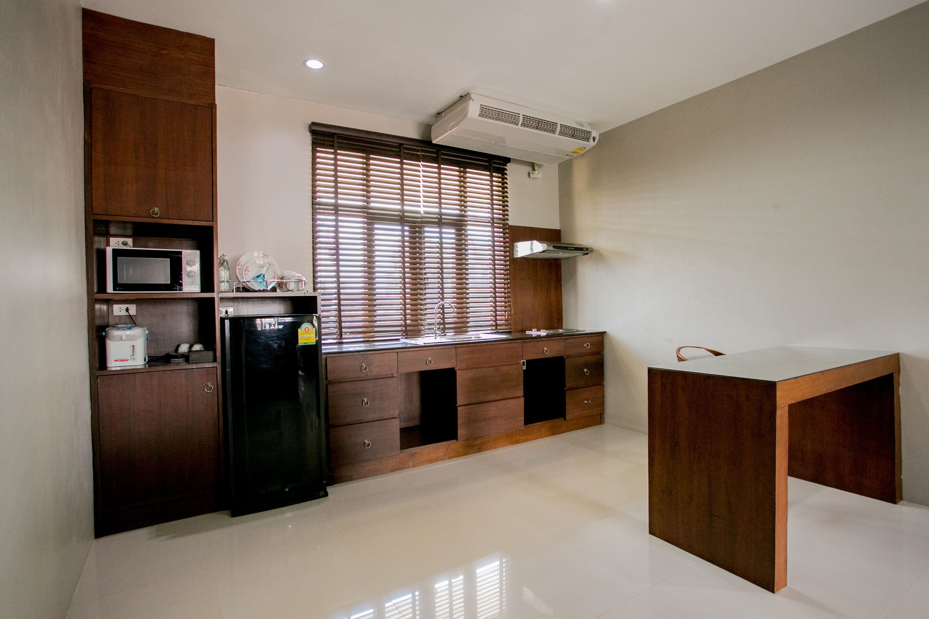 Una cocina moderna con armarios de madera, microondas integrado y refrigerador.