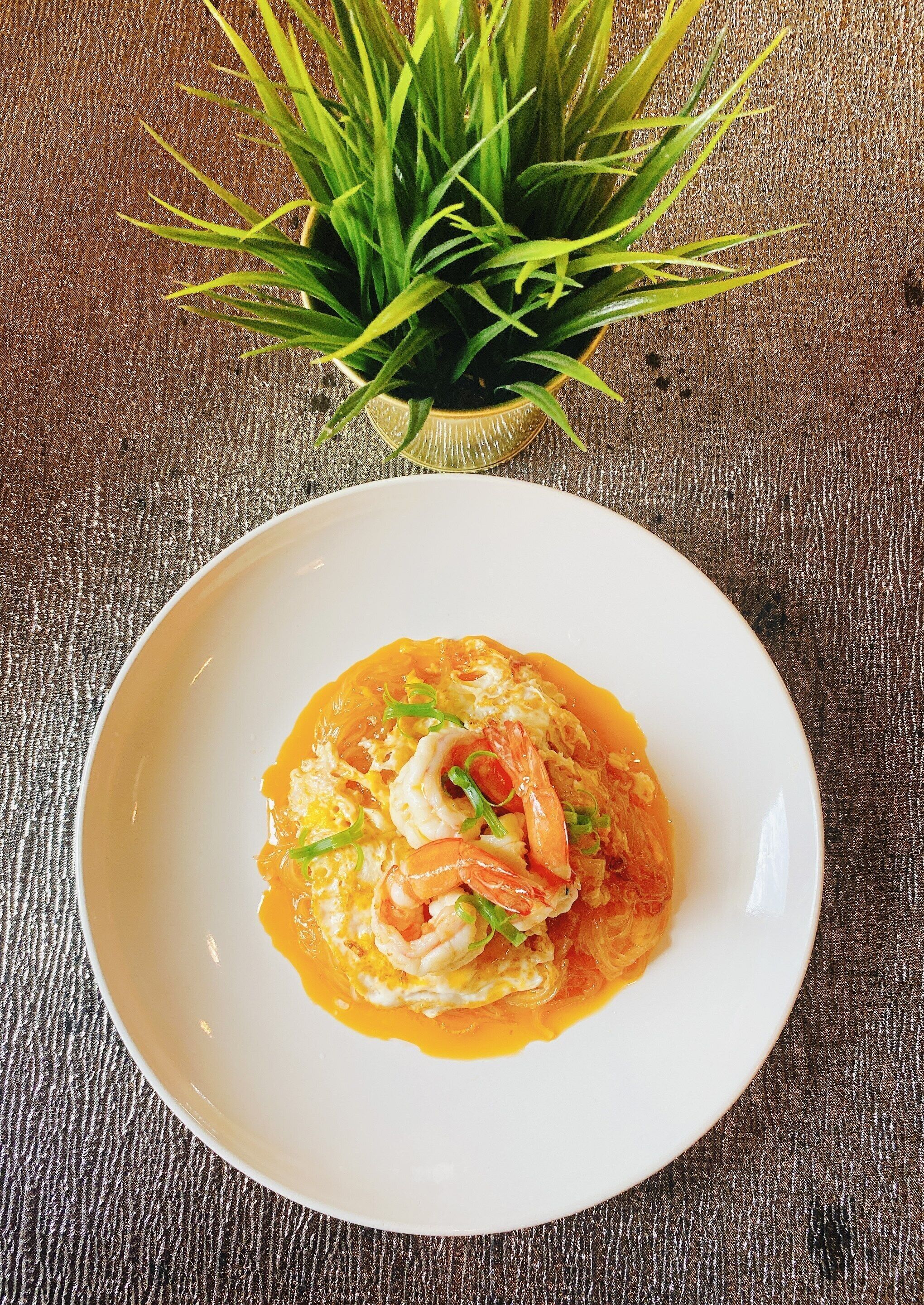 Un plato de comida con camarones y verduras sobre una superficie rugosa.