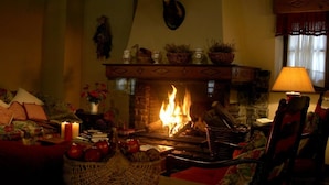 Una sala de estar acogedora con chimenea, una cesta de fruta y una lámpara.