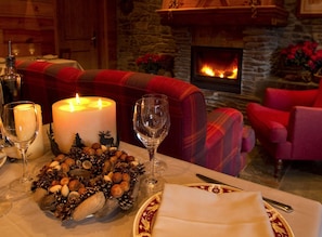 A cozy dining area with a fireplace, a table set with candles, wine glasses, and a decorative centerpiece. - Hotel Val de Ruda (Naut Aran)