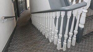 Un escalier avec des balustrades blanches, une main courante et un revêtement de sol en moquette.