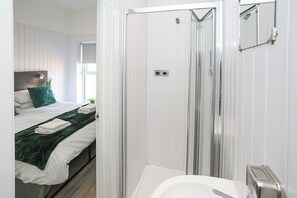 A modern bathroom with a glass shower enclosure, a white bathtub, and a visible toilet. - OYO Queens Quarter (Belfast)