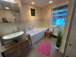 A modern bathroom with a bathtub, sink, and mirror.