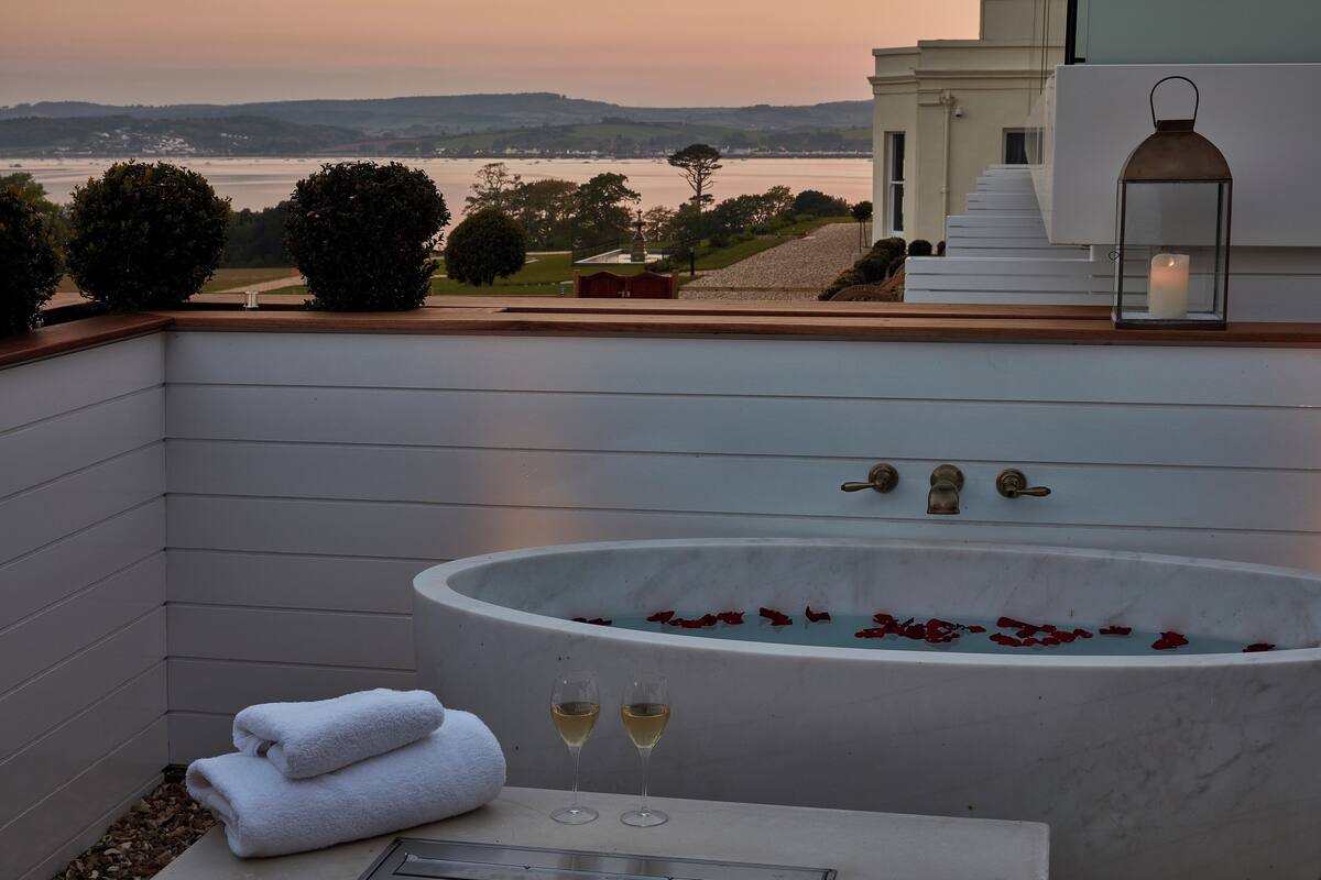 A spa area with a large bathtub, two glasses of wine, and towels.