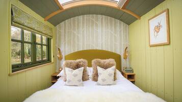 A room with a bed, two nightstands, a window with a view, and a framed picture on the wall.