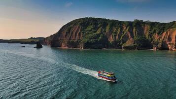A boat on a clear blue sea with cliffs in the background.