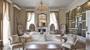 A spacious living room with a large sectional sofa, elegant chairs, a wooden coffee table, and a grand chandelier. - Lympstone Manor Hotel (Exmouth)