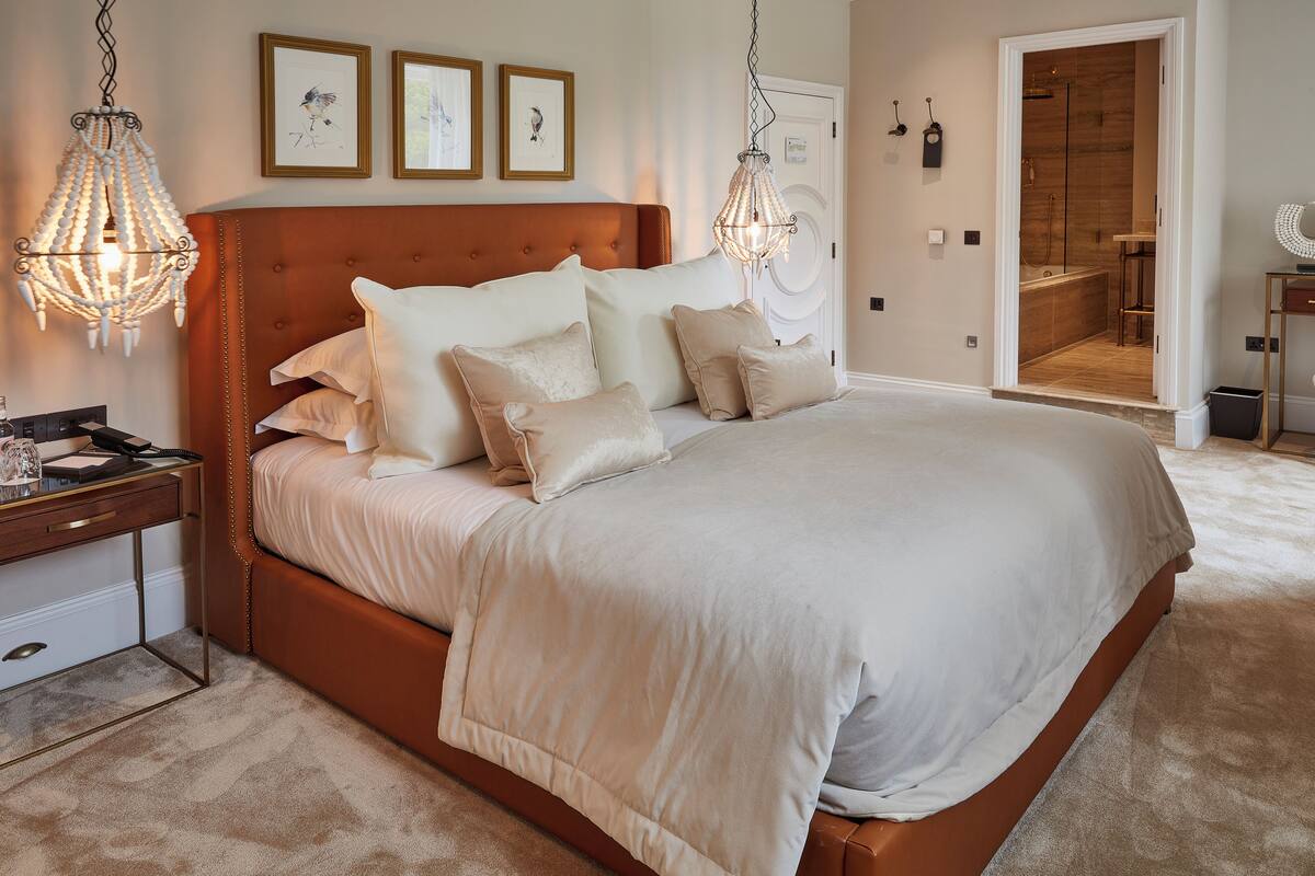 A spacious bedroom with a large bed, a bedside table, and a hanging light fixture.