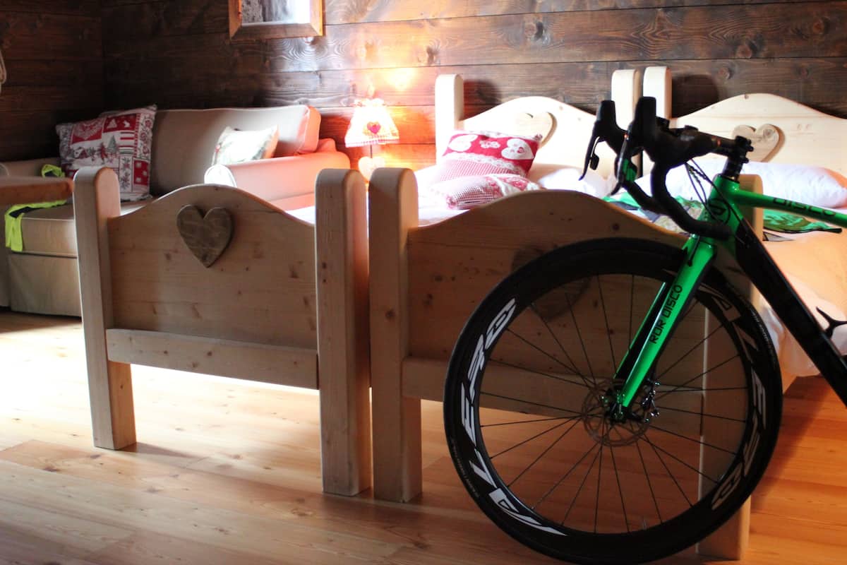 A wooden bed with a heart-shaped cutout, a green bicycle, and a wooden floor.