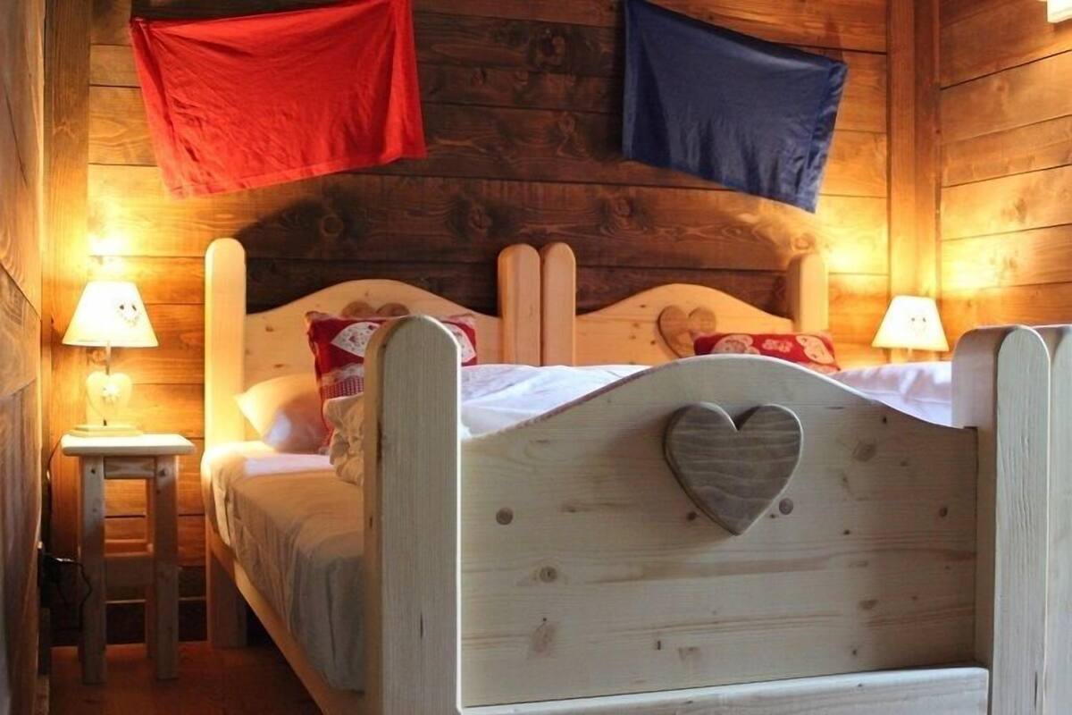 A wooden room with a bed, two nightstands, and a heart-shaped decoration on the bed frame.