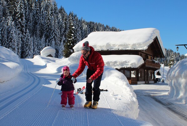 A snowy ski slope with a wooden cabin in the background.