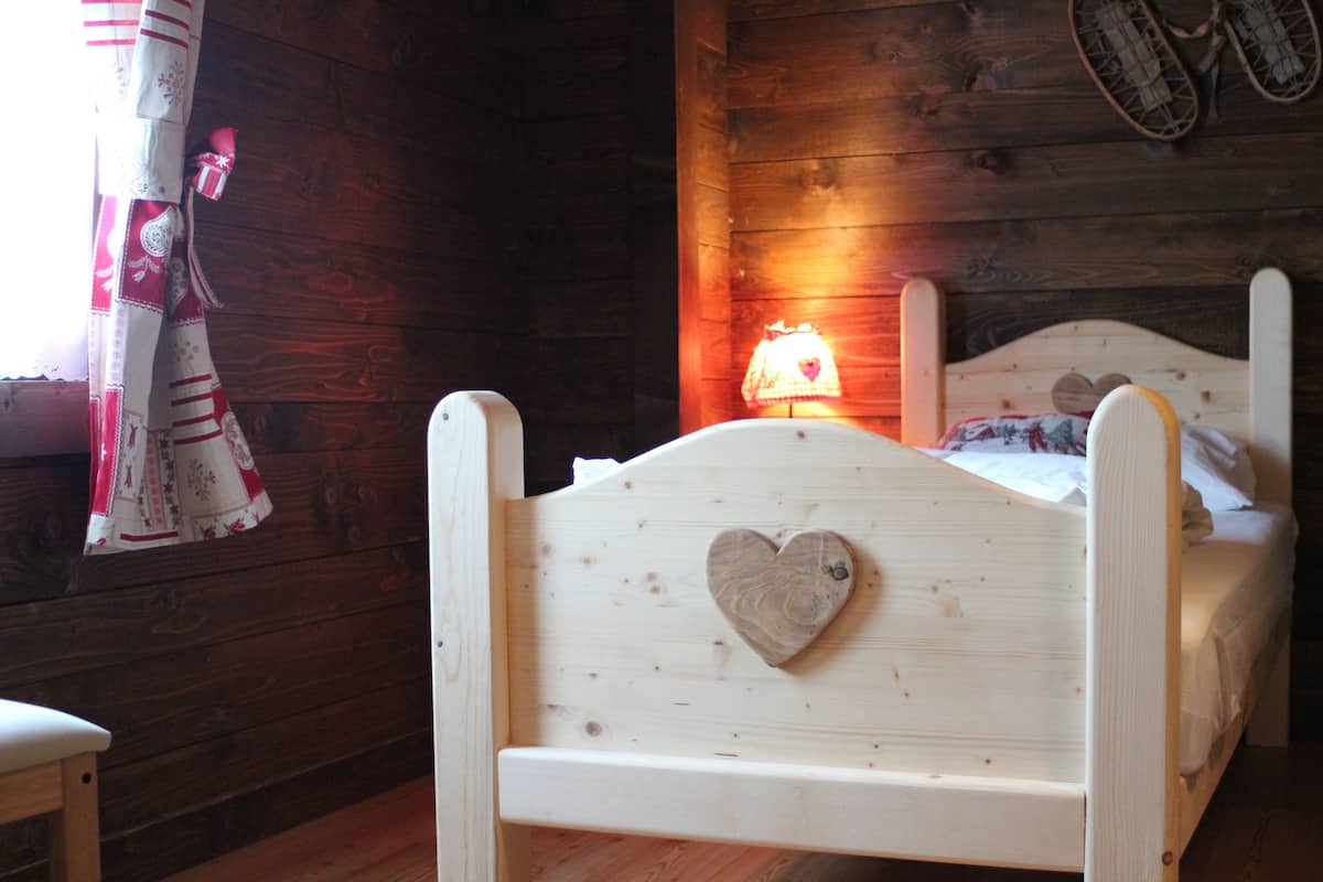 A wooden bed with a heart-shaped headboard, a bedside lamp, and a window with curtains.
