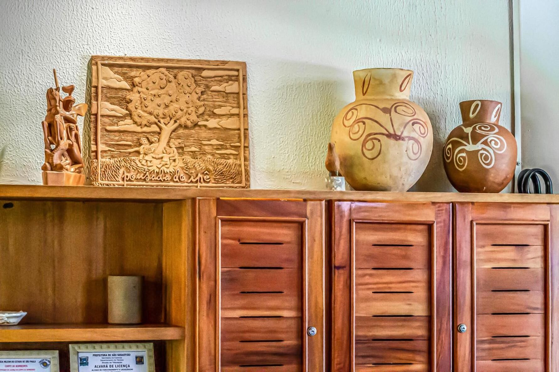 Un meuble en bois orné d’une plaque en bois sculptée, deux vases en céramique et une petite figurine.