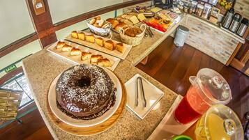 Un bufé con diferentes opciones de comida, incluyendo pasteles, productos de pastelería y un pastelón de chocolate.
