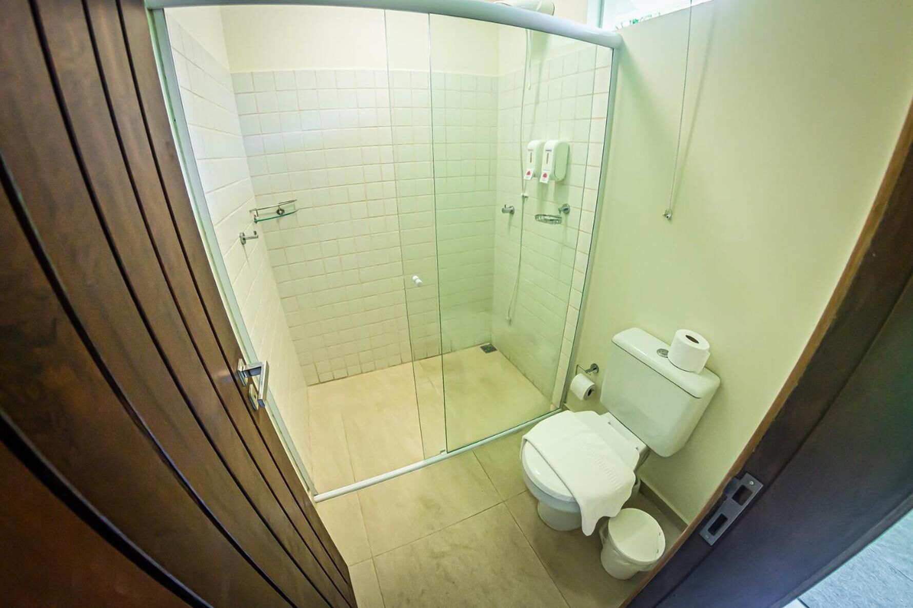 A compact bathroom with a glass shower enclosure, a toilet, and a sink.