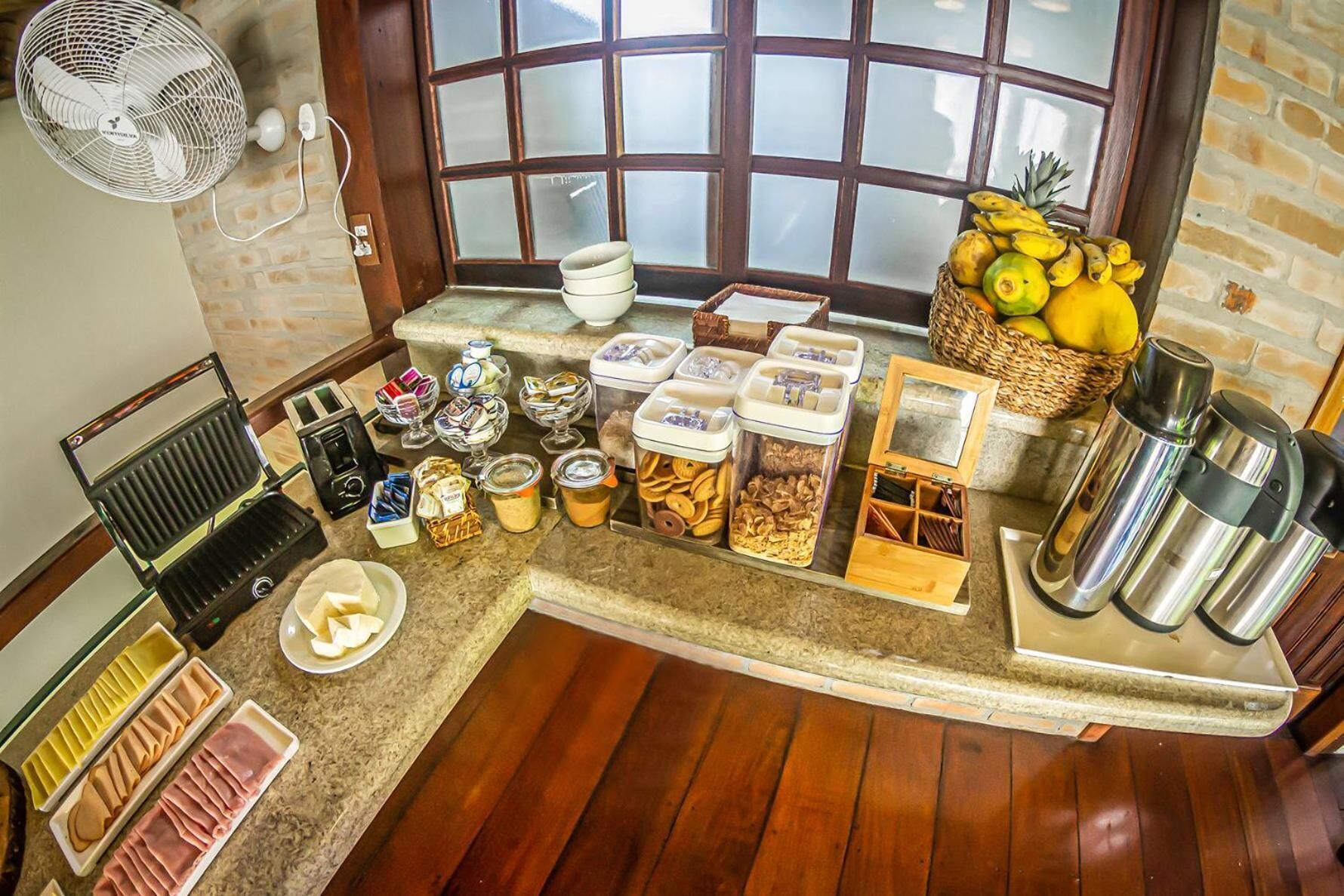 A breakfast bar with various food items, condiments, and a fan.