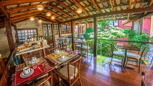A cozy restaurant with wooden beams and a balcony overlooking a garden. - Pousada Ipê (São Sebastião)