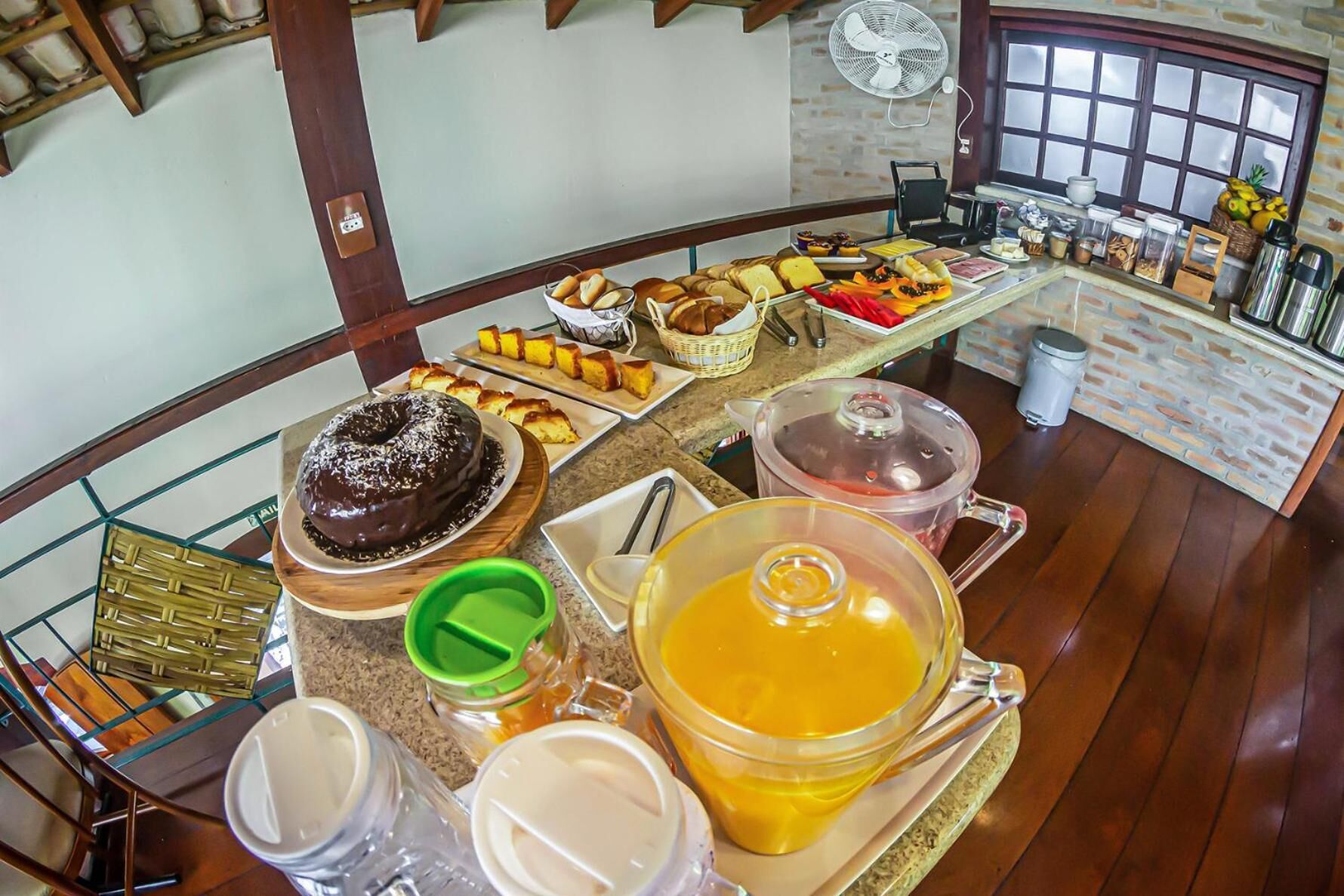 A breakfast buffet with various pastries, a chocolate cake, and a large bowl of orange juice.