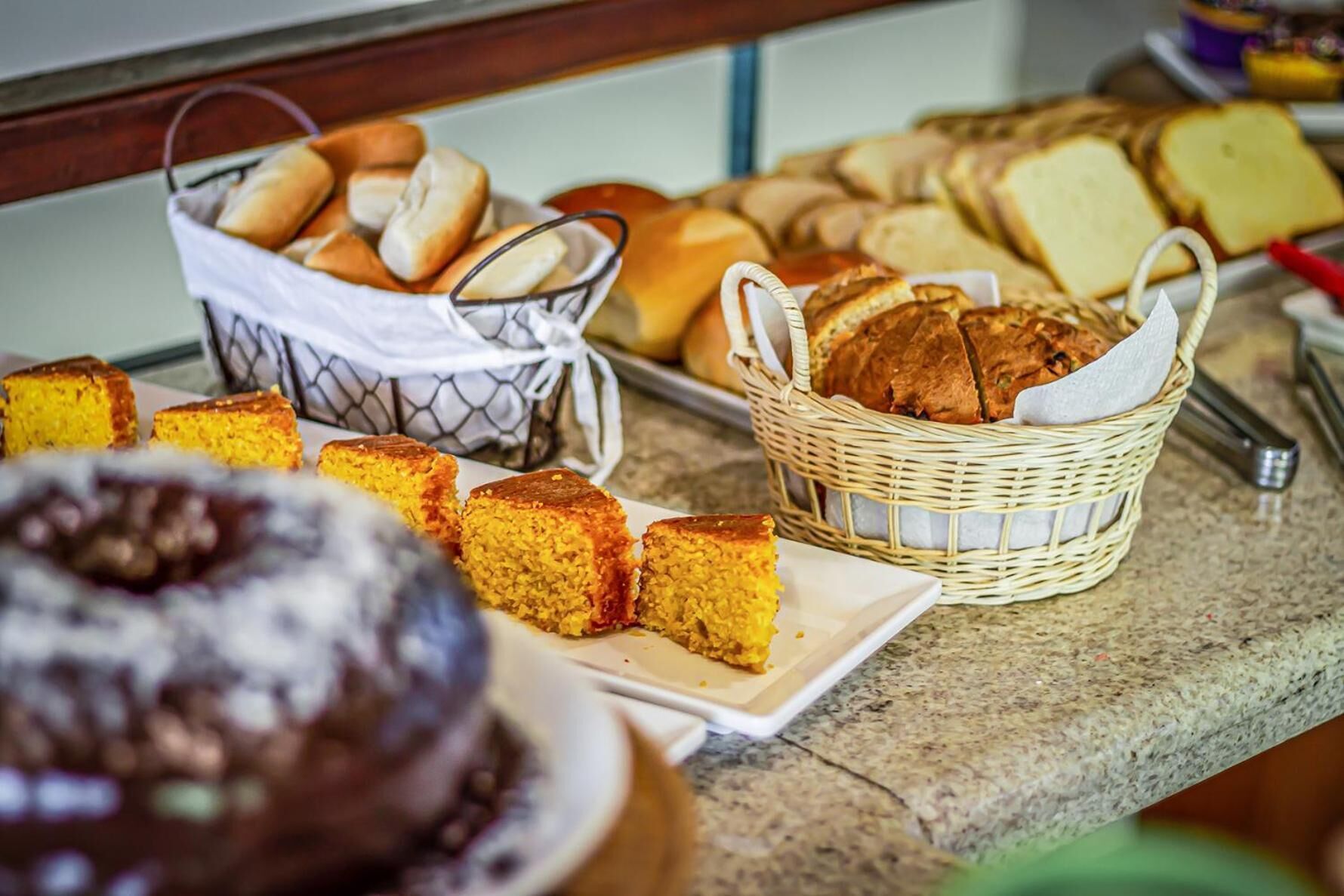 A buffet with various breads and cakes.