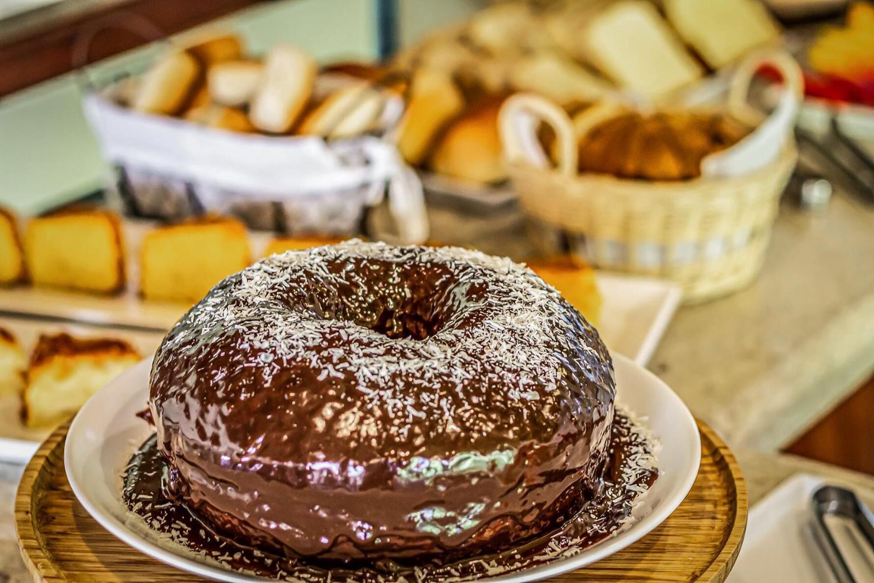 Un pastel bundt de chocolate con hojuelas de coco sobre una tabla de madera.