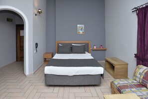 A bedroom with a bed, bedside tables, a nightstand, a wooden bench, a small shelf, a door, and a wall-mounted telephone.