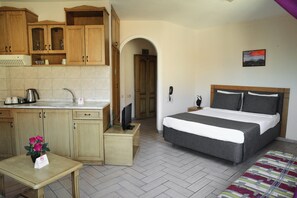 A compact hotel room with a kitchenette, a bed, and a small table with a flower arrangement. - Atak Apart Hotel (Alanya)