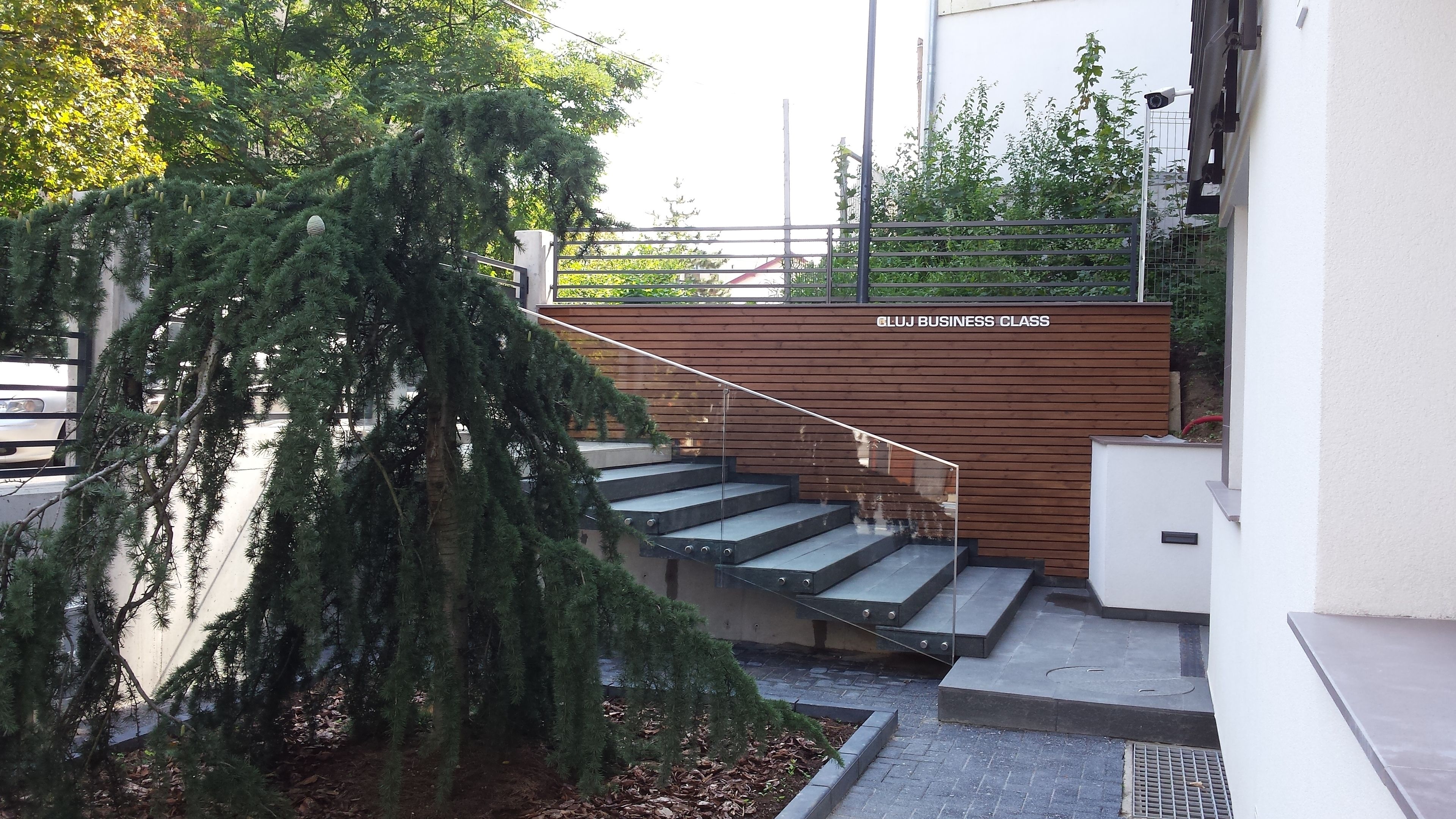 A staircase leading up to a building with a wooden fence and a tree in the foreground.