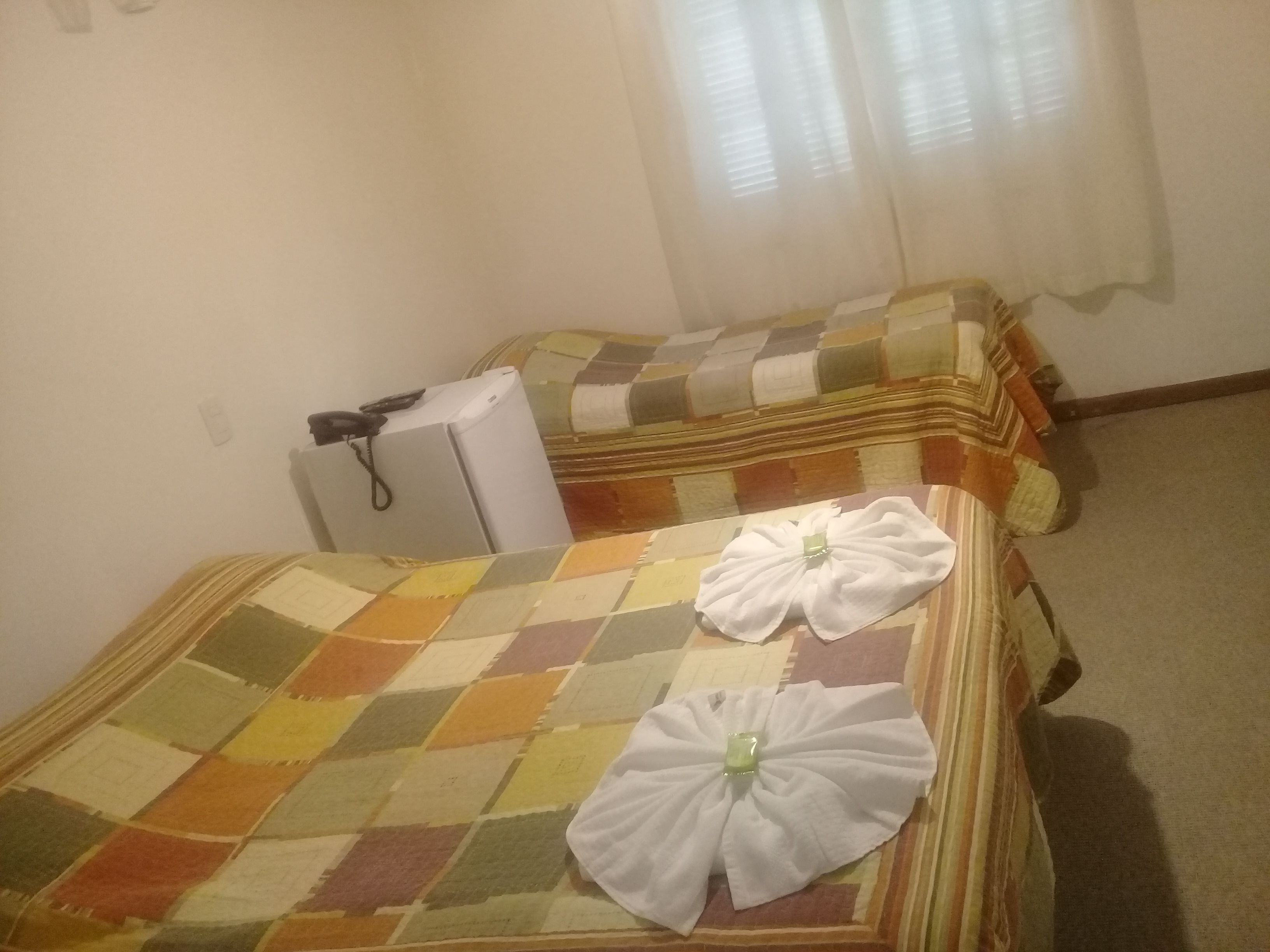 A room with two beds, each with a checkered bedspread and a white towel.