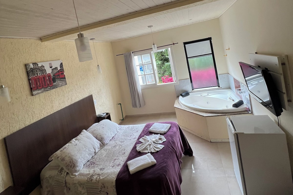 Une chambre à coucher comprenant un lit, un bureau, une chaise, une fenêtre et une salle de bain avec une baignoire.