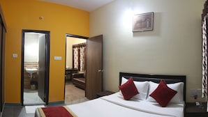 A hotel room with a bed, a nightstand, a mirror, and a door leading to a bathroom. - Tranzotel Bangalore Airport Hotel (Bengaluru)