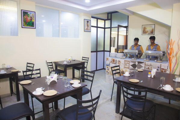 Comedor con mesas dispuestas para comidas, una estación de buffet y personal atendiendo.