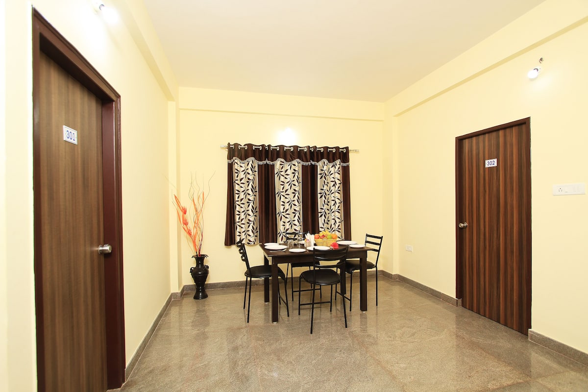 A hotel room with a dining area featuring a table set for four, two doors, and a potted plant.