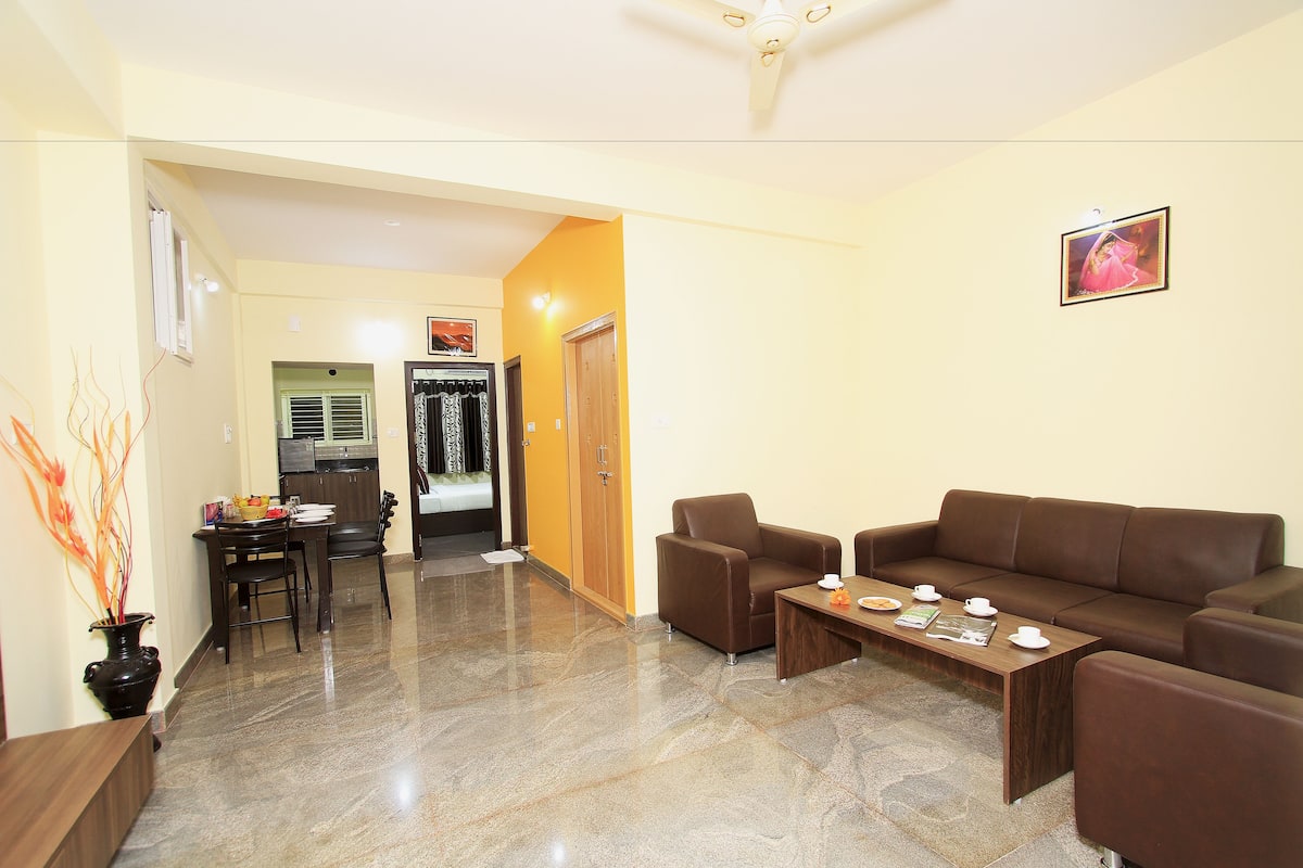 A modern living room with a brown leather sofa, a wooden coffee table, and a dining area with a table and chairs.