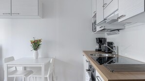 Une cuisine moderne avec des meubles blancs, un plan de travail en bois et un coin repas comprenant des chaises blanches et un vase de fleurs.