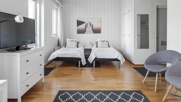 Une chambre moderne avec deux lits, une télévision et une armoire.