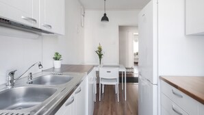 Une cuisine moderne avec des meubles blancs, des appareils en acier inoxydable et un plan de travail en bois.