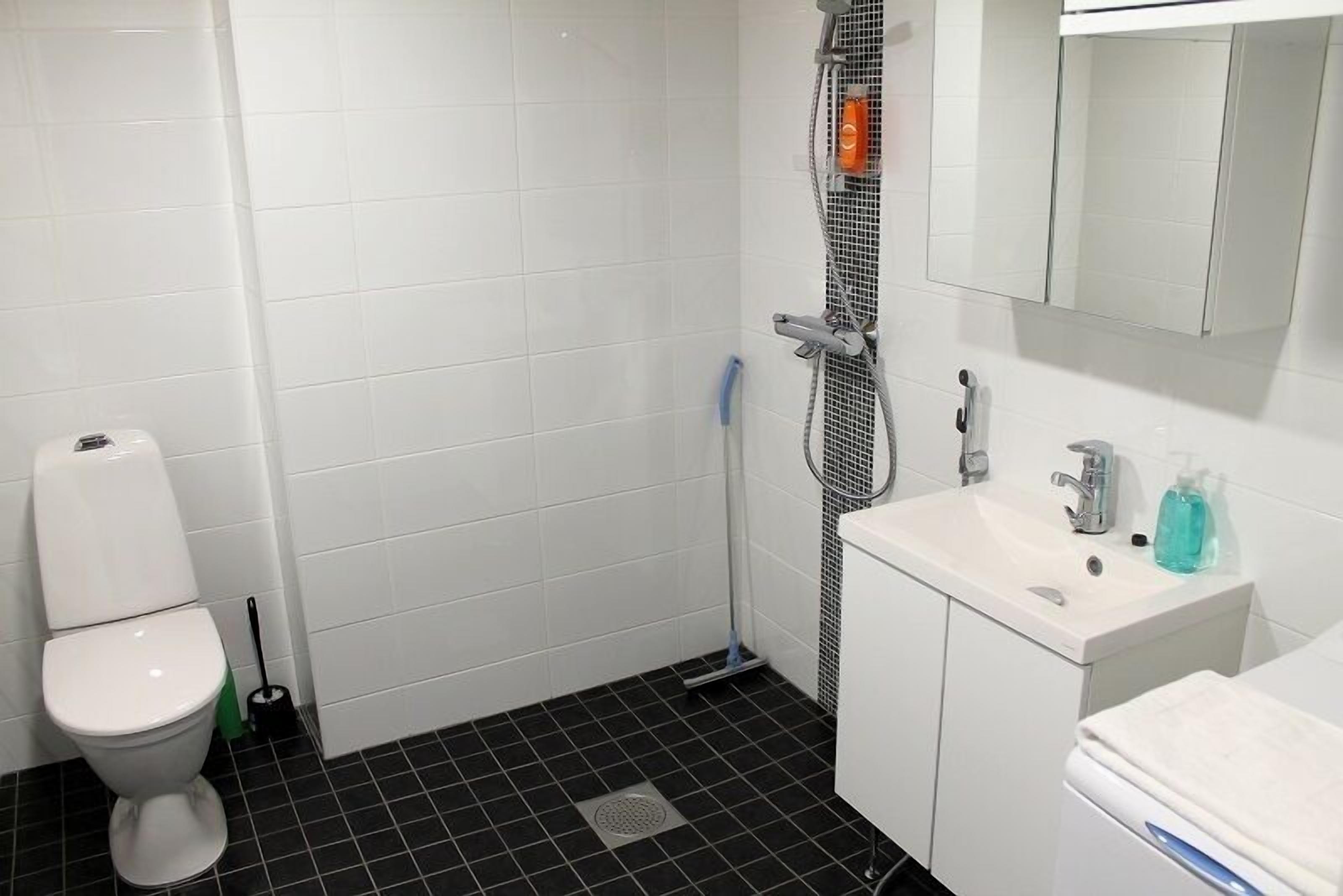 A bathroom with a toilet, a shower, and a sink.