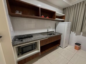 Una cocina compacta equipada con microondas, estufa, fregadero y refrigerador.