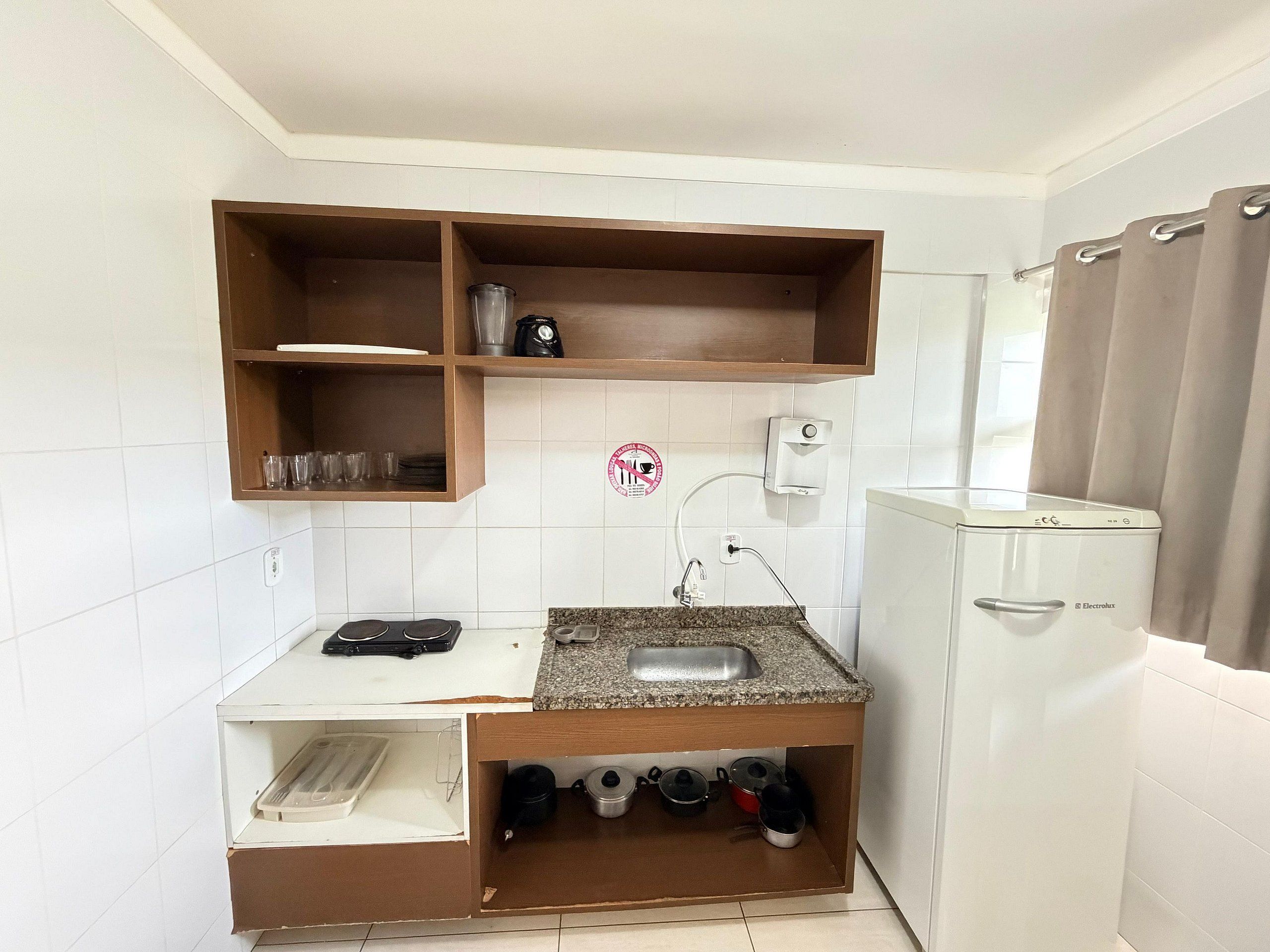 Una cocina compacta con un lavamanos integrado, una cafetera y un tendedero.