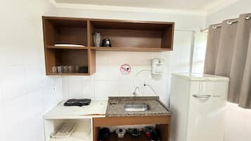 Una cocina compacta con un lavamanos integrado, una cafetera y un tendedero.