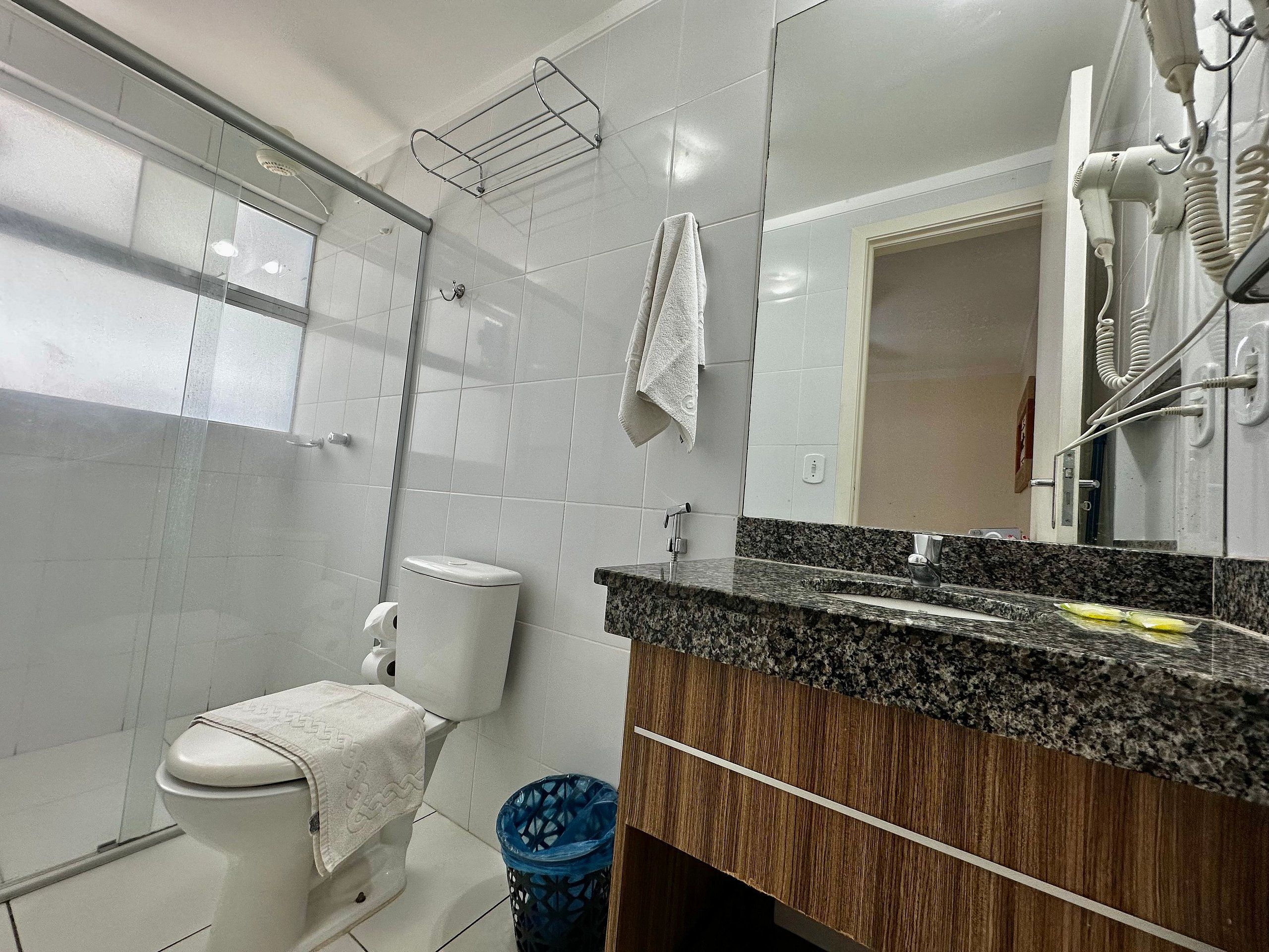 Un bagno con il water, lavabo, specchio e doccia.