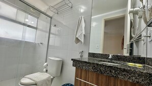 Un baño con inodoro, lavamanos, espejo y ducha.