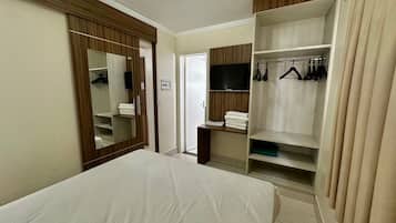 Camera d'albergo con un letto, un armadio pieno di vestiti, una televisione e uno specchio.