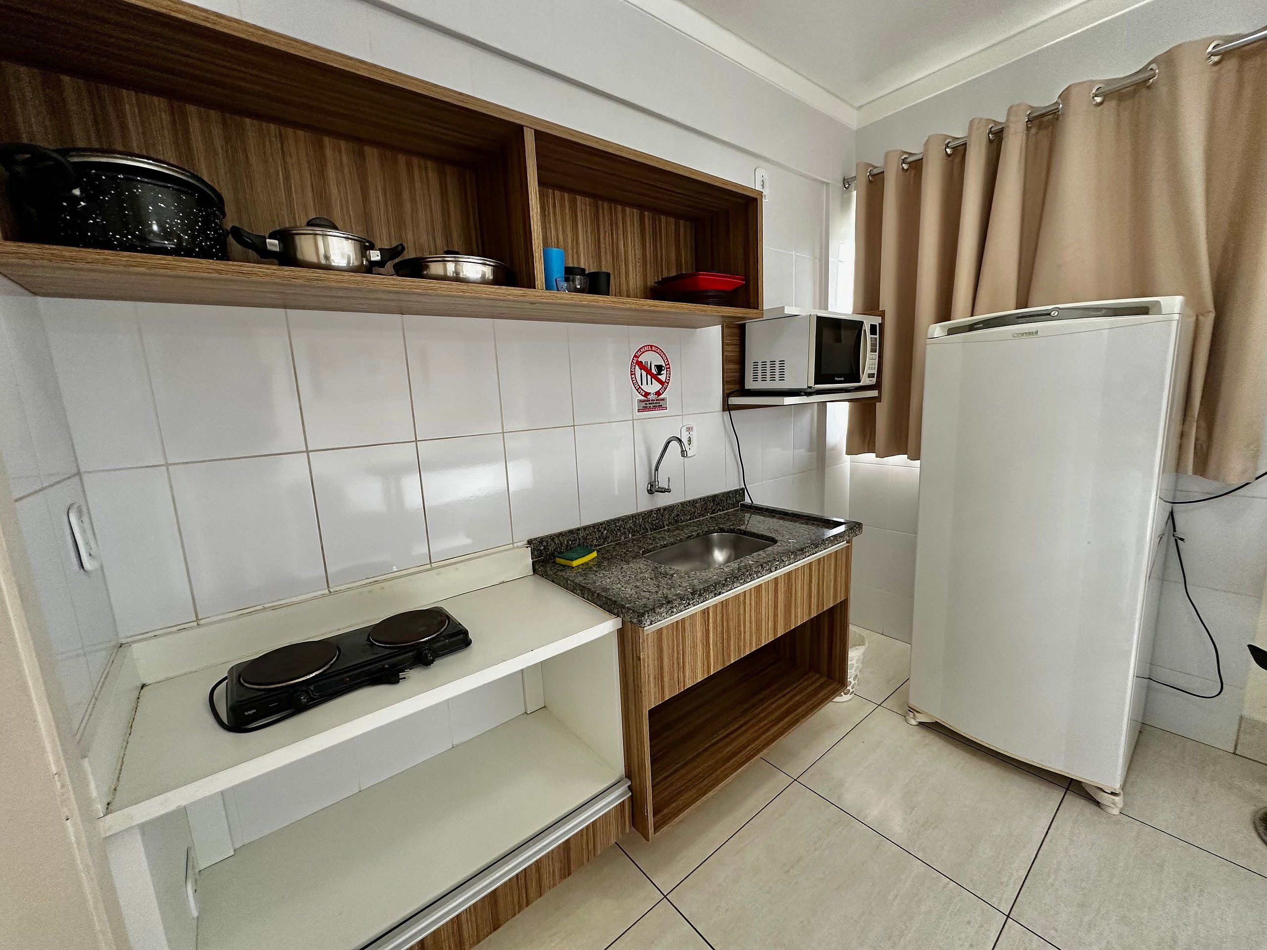 Una cucina compatta con forno a microonde, fornello e frigorifero.