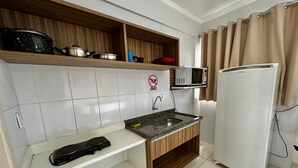 Cocina compacta con microondas, estufa y refrigerador.