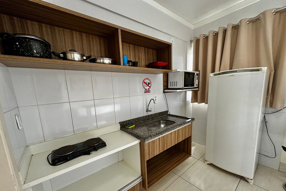 Cocina compacta con microondas, estufa y refrigerador.