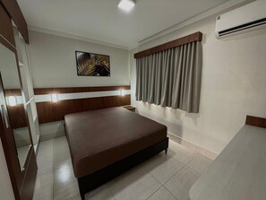 A hotel room with a bed, a painting on the wall, a window with curtains, and an air conditioning unit. - Lacqua DiRoma V Via Caldas (Caldas Novas)
